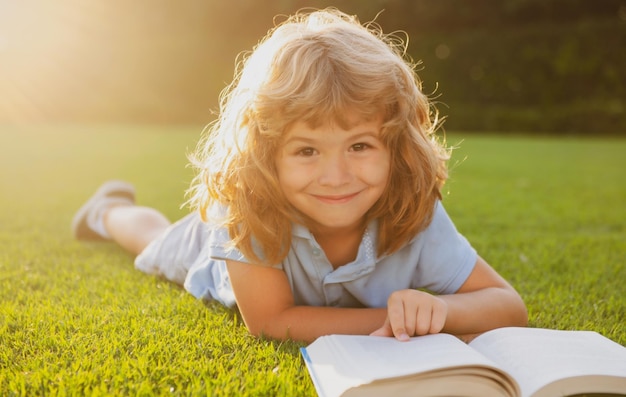 Porträt des glücklichen Kindjungen mit Buch im Park Früherziehung der Kinder Kleines Kind las Buch in der Garde