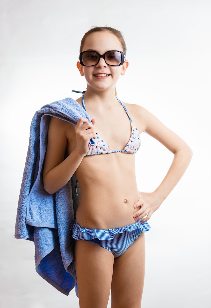 Foto porträt des glücklichen lächelnden mädchens in der sonnenbrille, das strandtuch hält