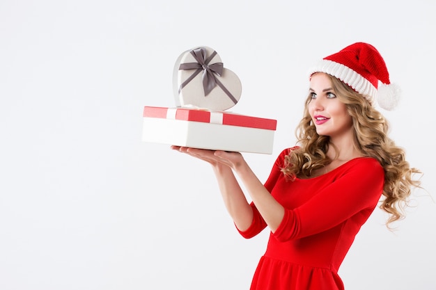 Porträt des glücklichen Mädchens in der Weihnachtsmannmütze mit Geschenkboxen