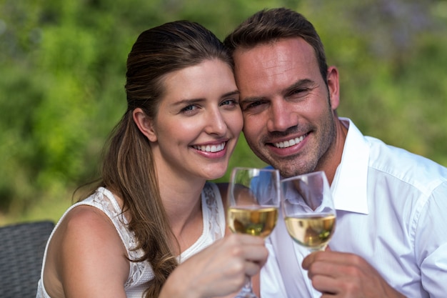 Porträt des glücklichen Paars Wein im Park genießend
