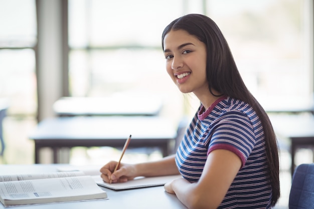 Porträt des glücklichen Schulmädchens, das im Klassenzimmer studiert