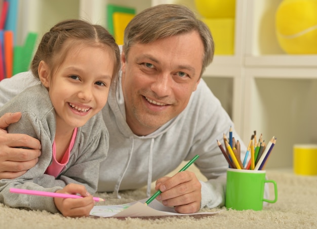 Porträt des glücklichen Vaters und der Tochter, die zu Hause malen