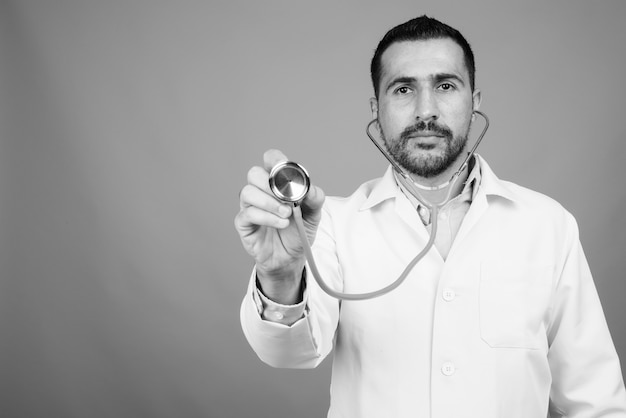 Porträt des gutaussehenden bärtigen persischen Arztes auf Grau in Schwarz und Weiß