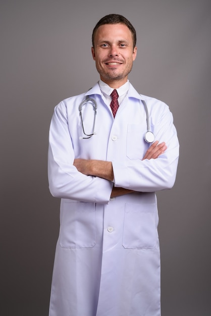 Porträt des gutaussehenden Mannarztes auf Grau