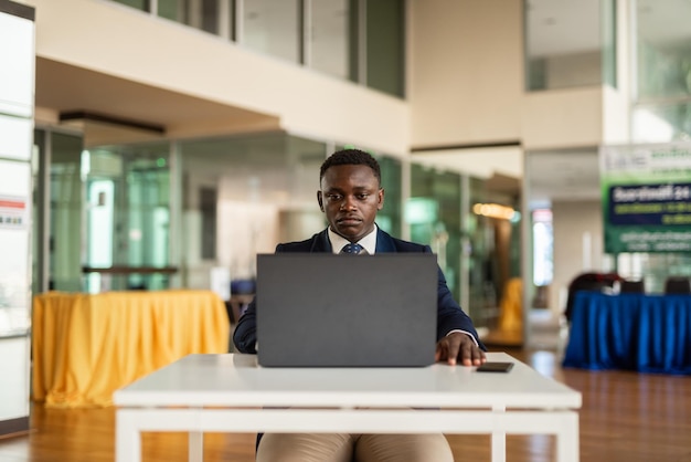 Porträt des hübschen afrikanischen Geschäftsmannes, der Laptop-Computer verwendet