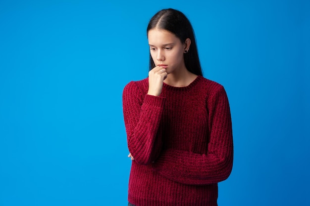 Porträt des hübschen jugendlich Mädchens, das Lösung gegen blauen Hintergrund denkt und schafft