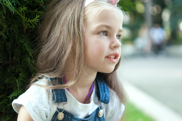 Porträt des hübschen Kindermädchens, das draußen im Sommerpark steht.