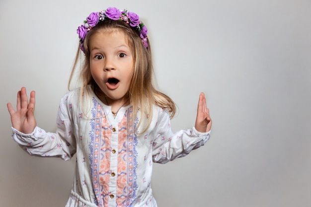 Porträt des hübschen kleinen Mädchens im weißen Kleid und im lila Kranz