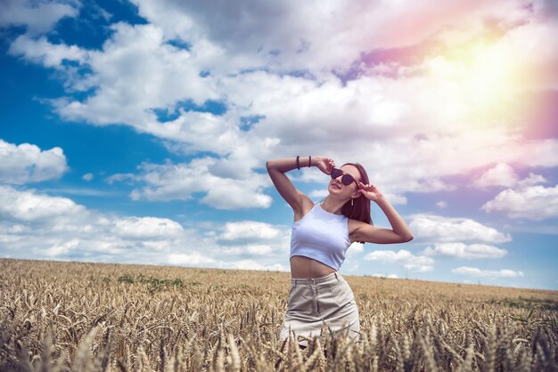 Porträt des hübschen Mädchens, das auf dem Hintergrund einer landwirtschaftlichen Feldsommerzeit aufwirft