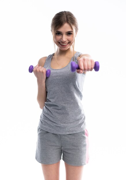 Porträt des hübschen sportlichen Mädchens, das Gewichte Hanteln hält und Übungen auf Weiß macht.