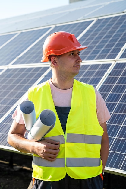 Porträt des Ingenieurs mit Bauplänen, die gegen Sonnenkollektoren posieren