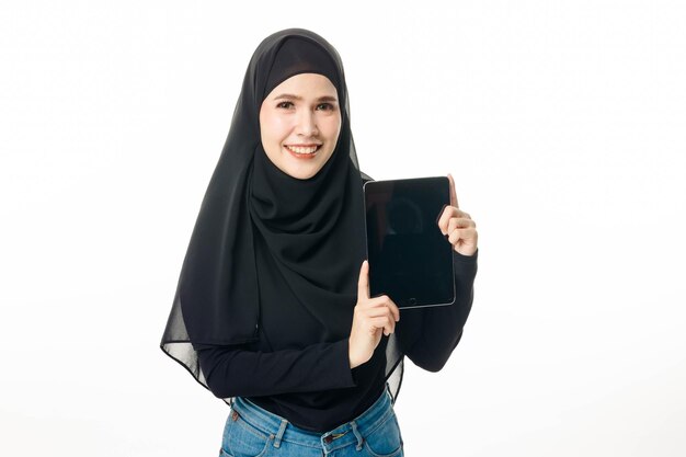 Porträt des islamischen Frauenmodells, das eine Tablette auf weißem lokalisiertem Hintergrund lächelt und hält