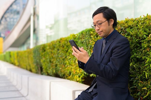 Porträt des japanischen Geschäftsmannes, der frische Luft mit Natur in der Stadt im Freien erhält