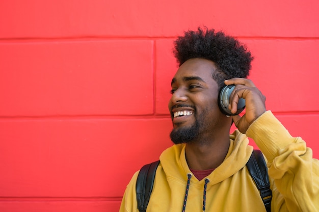 Porträt des jungen Afro-Mannes, der Musik mit Kopfhörern hört