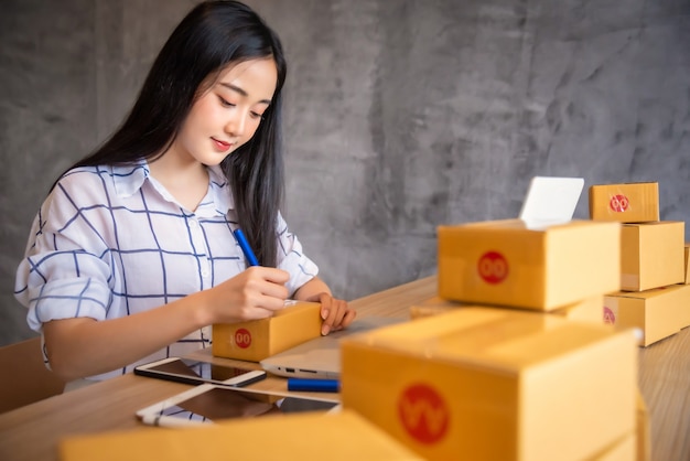 Porträt des jungen asiatischen arbeitenden Online-Einkaufs mit Laptop-Computer zu Hause. Online-Verkauf und Lieferkonzept