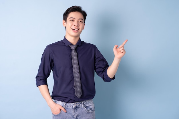 Porträt des jungen asiatischen Geschäftsmannes, der auf blauem Hintergrund aufwirft