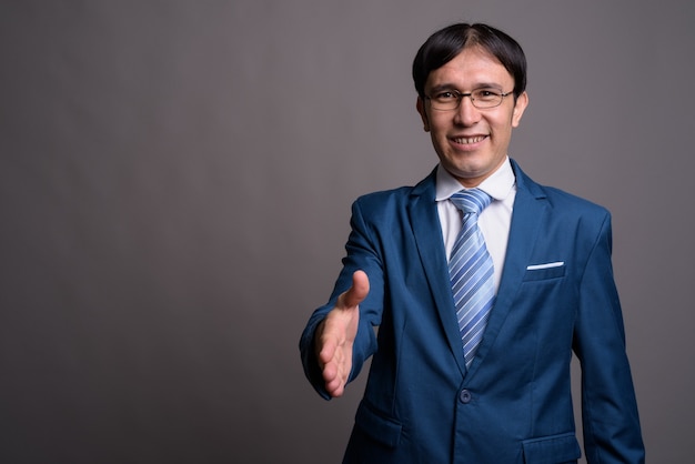 Porträt des jungen asiatischen geschäftsmannes gegen graue wand