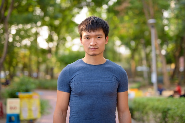Porträt des jungen asiatischen Mannes am Park im Freien