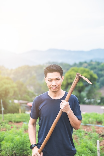 Porträt des jungen asiatischen Mannes, der im Garten arbeitet