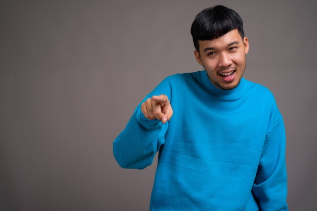 Porträt des jungen asiatischen Mannes gegen Grau