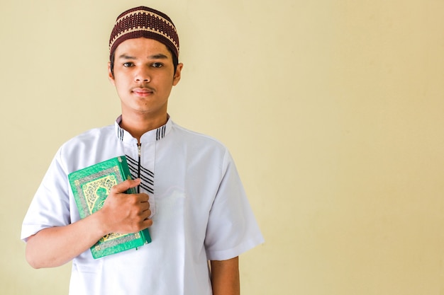 Porträt des jungen asiatischen Muslims, der das heilige Buch AlQuran hält