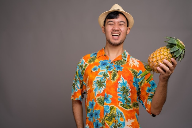 Porträt des jungen asiatischen Touristenmannes, der Ananas hält