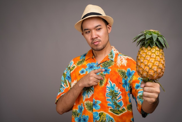 Porträt des jungen asiatischen Touristenmannes, der Ananas hält