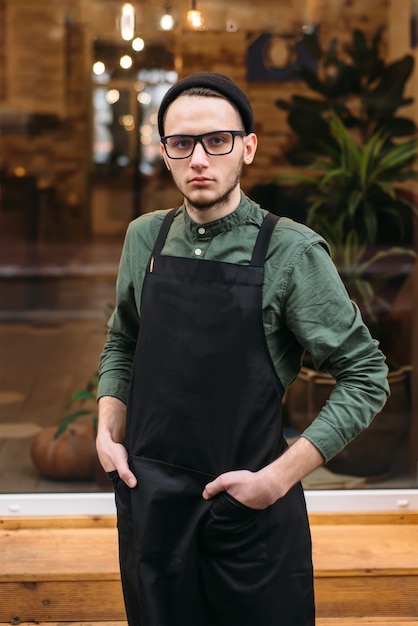 Porträt des jungen Barmanns in der schwarzen Schürze.