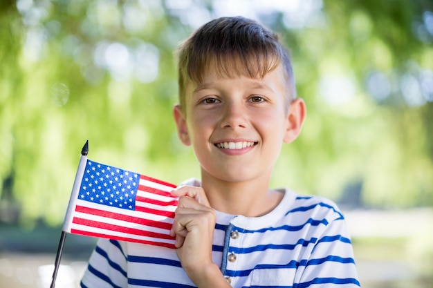 Porträt des Jungen, der eine amerikanische Flagge hält