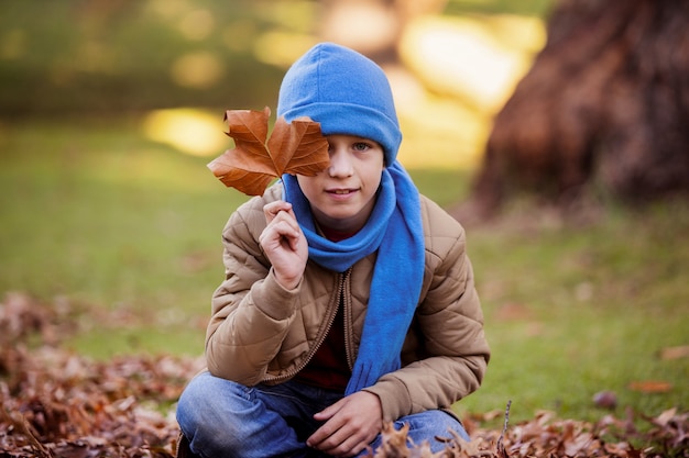 Porträt des Jungen, der Herbstblatt hält