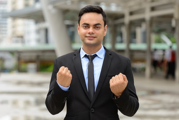 Porträt des jungen gutaussehenden indischen Geschäftsmannes in der Stadt