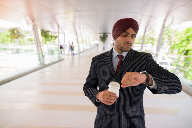 Porträt des jungen gutaussehenden indischen Sikh-Geschäftsmannes, der Turban trägt, während die Stadt Bangkok, Thailand erkundet