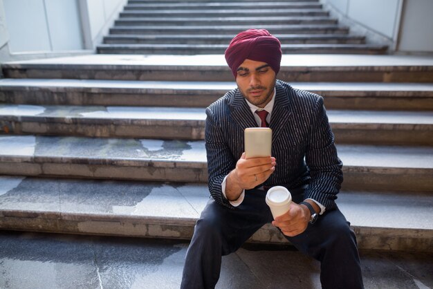 Porträt des jungen gutaussehenden indischen Sikh-Geschäftsmannes, der Turban trägt, während die Stadt Bangkok, Thailand erkundet