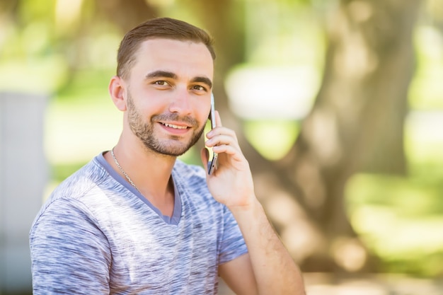 Porträt des jungen gutaussehenden jungen Mannes, der am Handy spricht