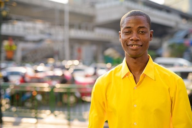 Porträt des jungen gutaussehenden kahlen afrikanischen Geschäftsmannes, der die Stadtstraßen von Bangkok erkundet