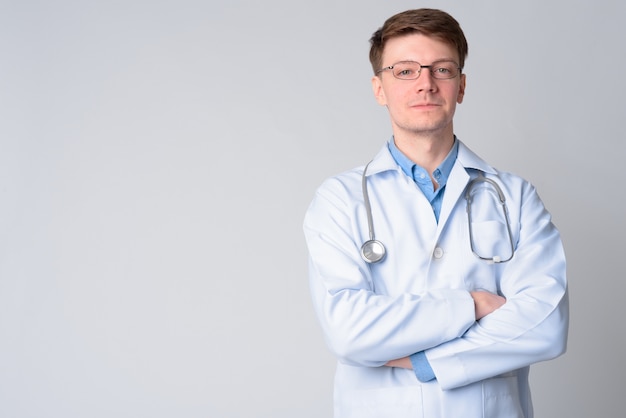 Porträt des jungen gutaussehenden Mannarztes mit Brillen, die Arme kreuzen