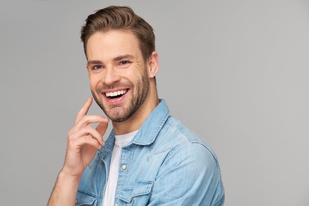 Porträt des jungen gutaussehenden Mannes im Jeanshemd über heller Wand