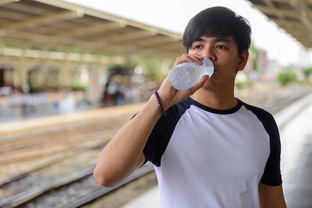 Porträt des jungen gutaussehenden philippinischen Touristenmannes am Bahnhof Hua Lamphong in Bangkok