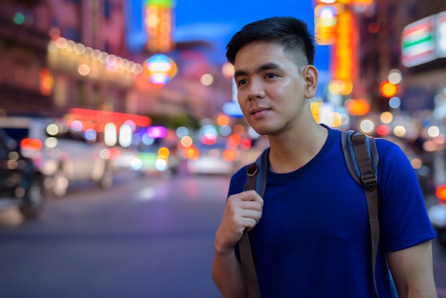 Porträt des jungen hübschen asiatischen Touristenmanns, der Chinatown in Bangkok, Thailand erforscht