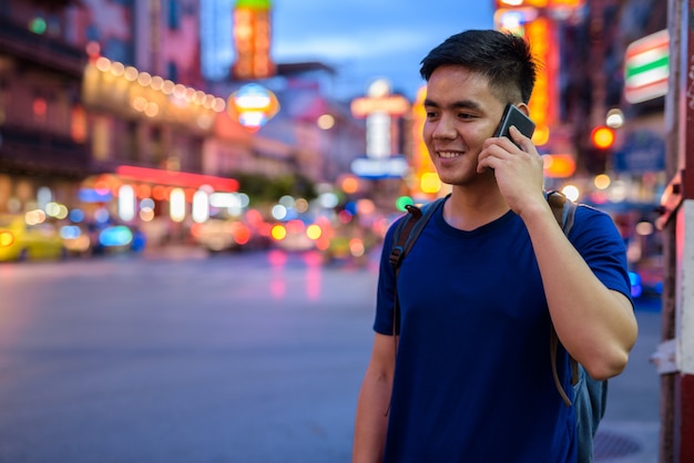 Porträt des jungen hübschen asiatischen Touristenmanns, der Chinatown in Bangkok, Thailand erforscht