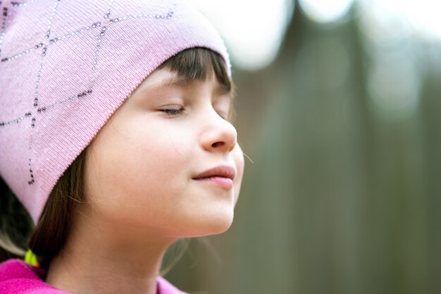 Porträt des jungen hübschen Kindermädchens, das rosa Jacke und Mütze trägt