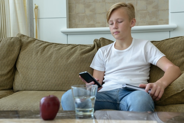 Porträt des jungen hübschen skandinavischen Jungen mit blonden Haaren im Wohnzimmer zu Hause