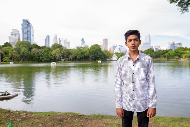 Porträt des jungen indischen Teenagers, der am Park entspannt
