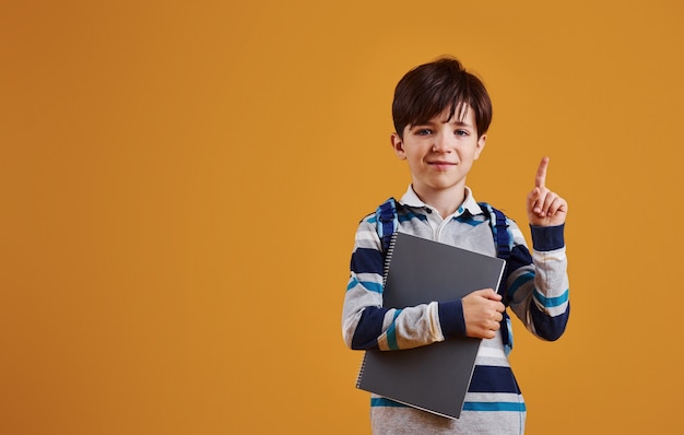 Porträt des jungen intelligenten Schülers im Studio gegen gelben Hintergrund.