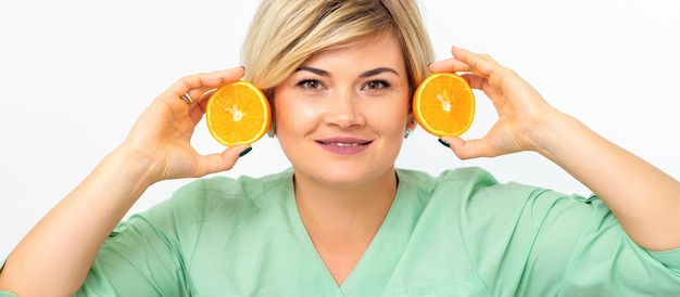Porträt des jungen lächelnden blonden Frauenkosmetikers mit Hälften von Orangen auf weißem Hintergrund.