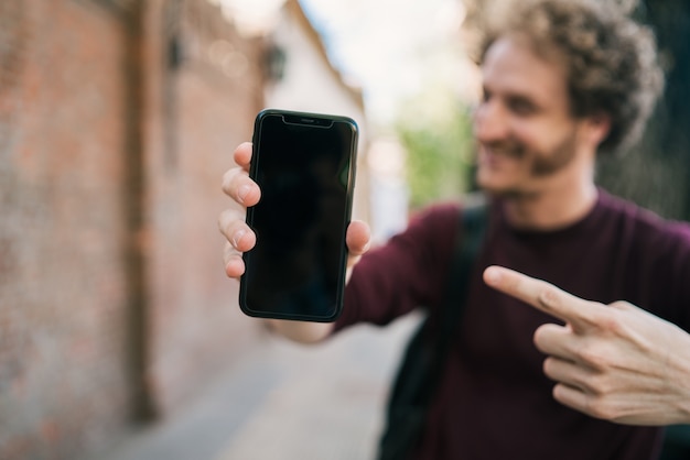 Porträt des jungen Mannes, der leeren Smartphonebildschirm zeigt