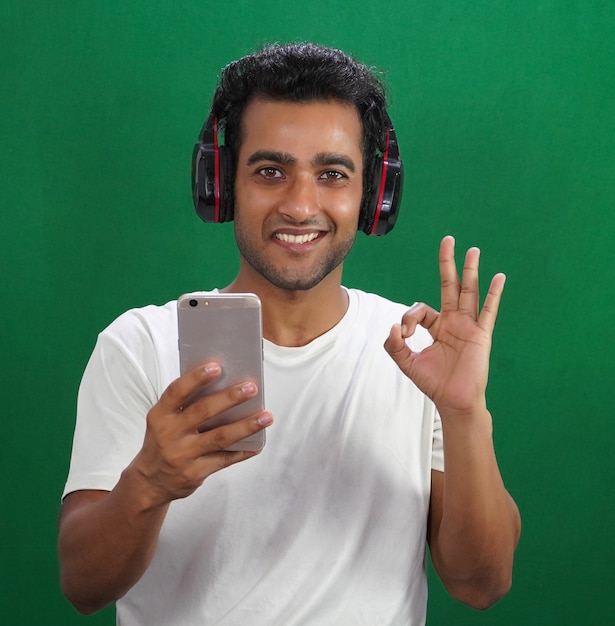 Porträt des jungen Mannes mit Kopfhörern und Telefon