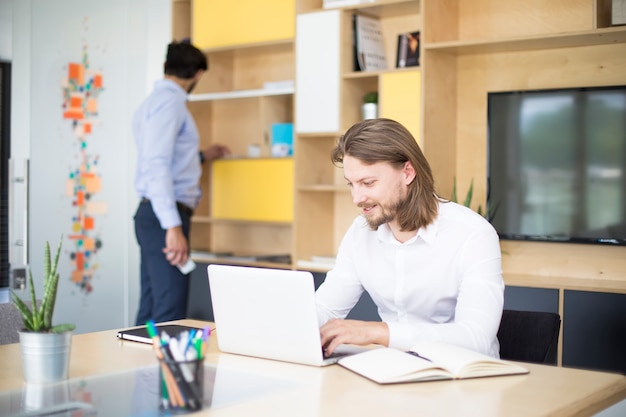 Porträt des jungen Mannes sitzend an seinem Schreibtisch im Büro