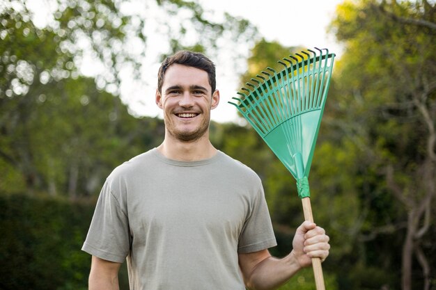 Porträt des jungen Mannes stehend mit einer Gartenarbeitstange im Garten