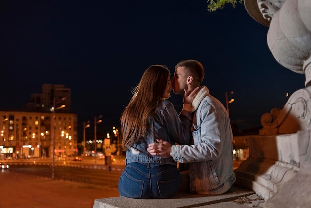 Porträt des jungen Paares umarmt und küsst sich auf dem Hintergrund der Abendstadt Datum in der Stadt